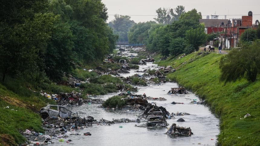 Un río sucio con basura y residuos, reflejando la falta de cuidado ambiental.